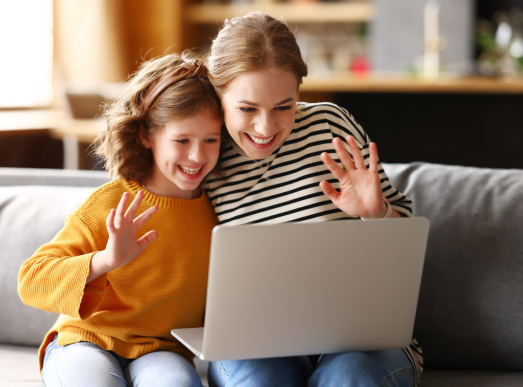 Mom and daughter talking with family online while relaxing together at home